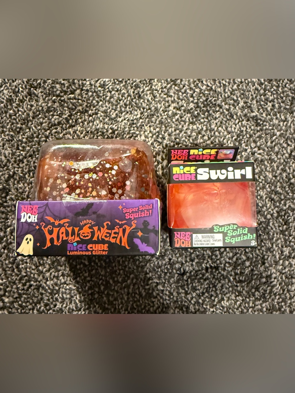 2 orange squishys. (1) Halloween Luminous Glitter Squish, (1) Needoh swirl